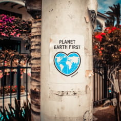 Affiche de Greenpeace 'Planet earth first' sur un poteau dans l'espace public devant un bâtiment privé