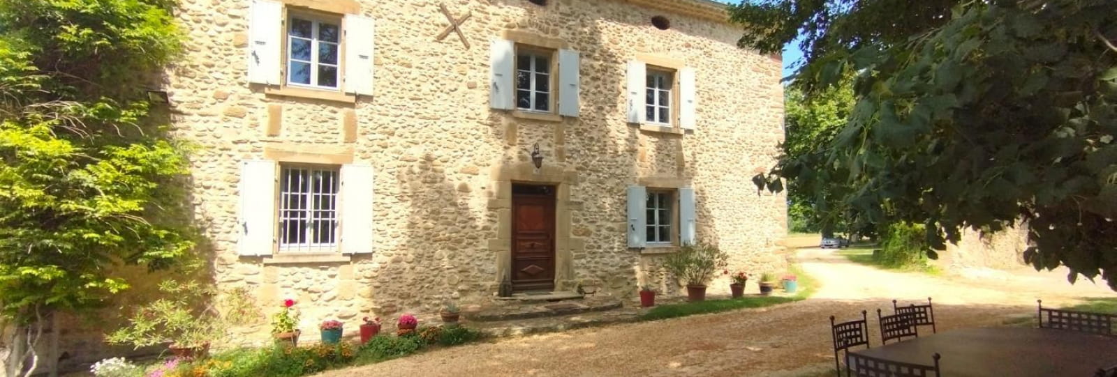 Entrée du gîte et salon de jardin à l'ombre de l'arbre