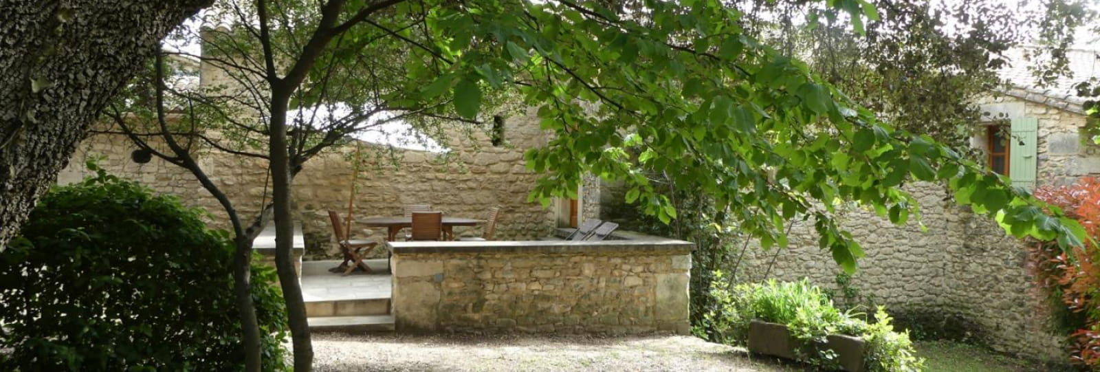 terrasse bois ombragée et terrasse en pierre ensoleillée à l'entrée du gîte